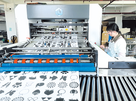 渔沟镇精彩飞扬公司生产车间内，工人正加紧生产...